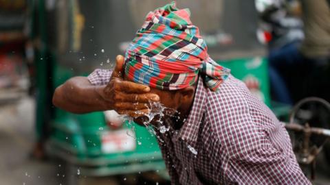 A rickshaw puller splashes water on his face to get relief during a heatwave in Dhaka, Bangladesh