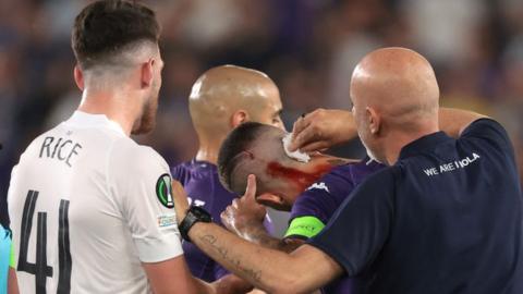 Cristiano Biraghi of Fiorentina receives treatment for a wound to the head after appearing to be struck by an object