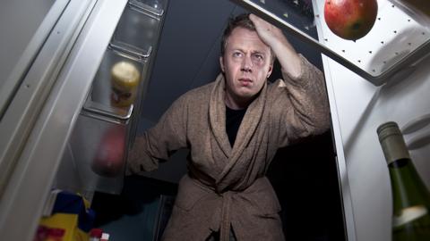 man looks in fridge at night