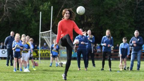 Kate kicks a Gaelic football during a visit to Salthill Knocknacarra GAA club
