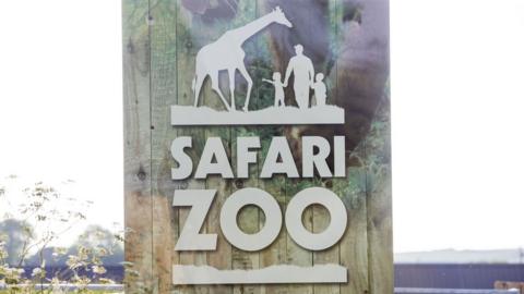 A sign with the zoo name and logo