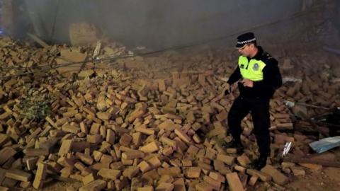 A policeman looks for victims in the rubble minutes after the collapse of the old Parravicini movie theater building, in Tucuman, Argentina on May 23, 2018.