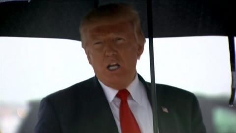 Trump under an umbrella.