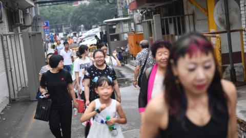 People walk in an alley behind a commercial district in Beijing.