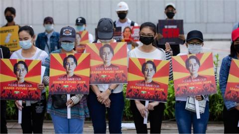 Protesters wearing face masks hold placards with the portraits of Aung San Suu Kyi during the demonstration.