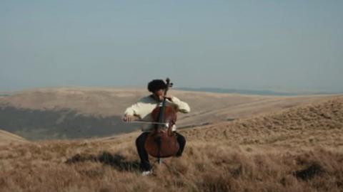 Sheku Kanneh-Masoj yn chwarae'r soddgrwth ar ben mynydd