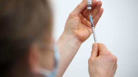 Close-up of a medic, holding a syringe and vial, preparing an injection of the Pfizer-BioNTech vaccine, Feb 2021