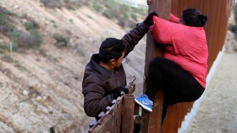 Migrants from Honduras, part of a caravan of thousands from Central America trying to reach the United States, jump a border fence to cross illegally from Mexico into the US, in Tijuana, Mexico, 27 December 2018