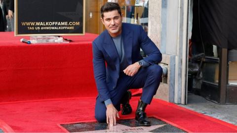 Zac Efron touching his star the Hollywood Walk of Fame