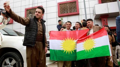 Kurds take pictures with Kurdish flags at the Kirkuk Governorate Council building in Kirkuk, Iraq (6 April 2017)