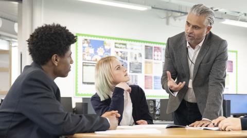 A teacher talks to pupils in a classroom