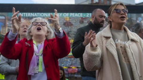 People sing at a gathering to mark the 25th anniversary of the Good Friday Agreement