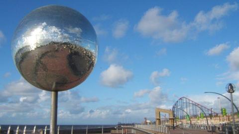 The large glitterball on the south promenade Blackpool with the Pleasure Beach in the background.
