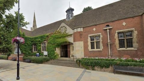 Brick-and-stone built single-storey building alongside wide pavement