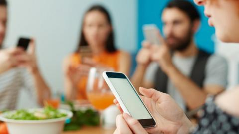 People on phones at table