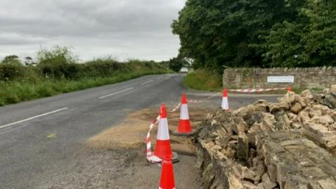 The crash scene with cones around a wall