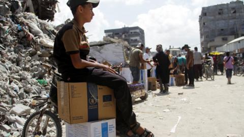 A Palestinian boy sits on boxes of food aid distributed by the UN's World Food Programme in Jabalia, in the northern Gaza Strip (24 August 2024)