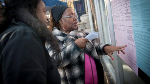 A volunteer talks about ballot measures with a voter outside a polling location for the 2016 US presidential election after polls opened at Wright's Barber Shop in Philadelphia, Pennsylvania, 8 November