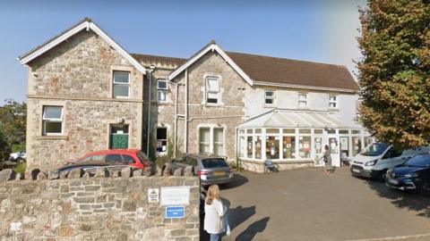 A GP practice with stone walls and a conservatory