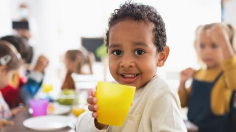 a toddler holding a yellow cup