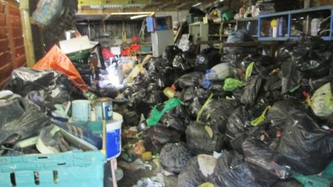 Black bin bags of rubbish piled up in a garage