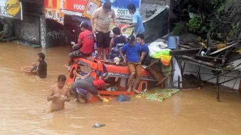 People seat on a partially submerged vehicle in Cagayan de Oro, Philippines.