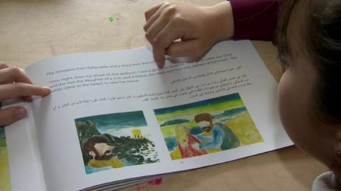 Syrian pupil reading a bilingual school book in both Arabic and English