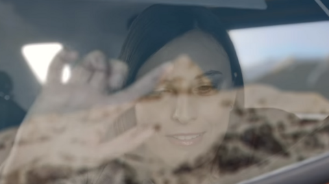 Woman traces landscape on car window