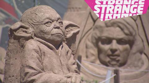 A sand sculpture of yoda and the strange logo