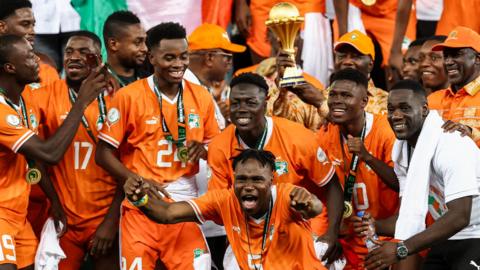 Ivory Coast players celebrate with the Africa Cup of Nations trophy after beating Nigeria