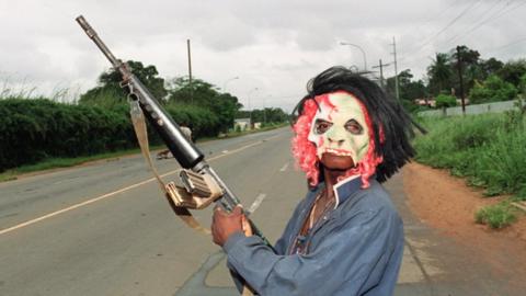 A masked rebel loyal to warlord Charles Taylor of the National Patriotic Front of Liberia (NPFL) holding a machine-gun patrol in the streets of Monrovia 11 August 1990