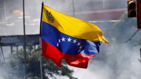 A demonstrator waves a Venezuelan flag during riots at a march to state Ombudsman"s office in Caracas, Venezuela May 29, 2017.