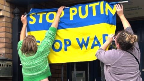 women hoist ukrainian flag call for an end to the war