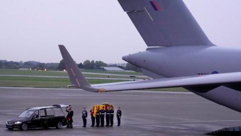 The Queen's coffin is carried from the military plane that flew it to RAF Northolt