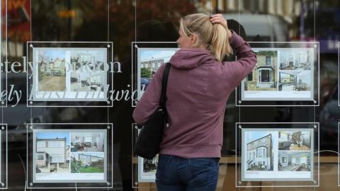 Woman looks in estate agent wndow