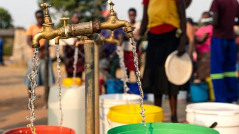 People queue to collect bucket loads of water from a borehole in Glen View, Harare, Zimbabwe - archive shot