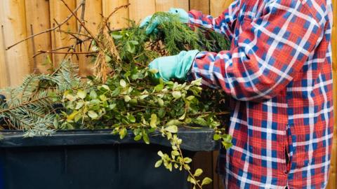 PErson putting garden waste into bin