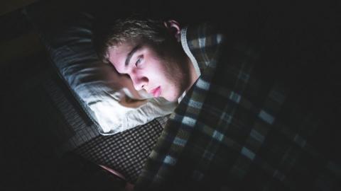 Teenage boy on social media while in bed in the dark