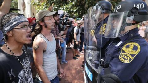 Virginia State Police wear body armour and use riot shields while keeping crowds away from alt-right blogger Jason Kessler after he tried to hold a news conference on 13 August 2017