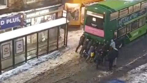 Youths help free a bus in snow