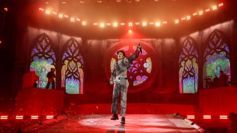 Oli Sykes of Bring Me the Horizon jumping on the stage which has been designed like a church