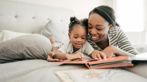 A woman reading on the bed with her toddler