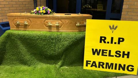 a coffin with a sign in front of it reading 'RIP Welsh farming'