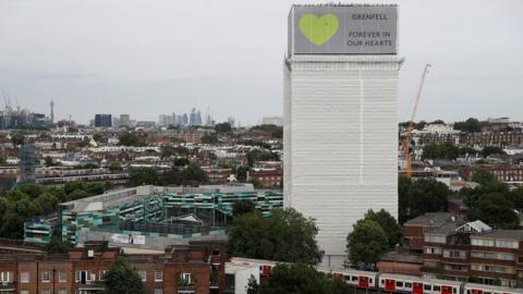 Grenfell Tower is seen shrouded by scaffolding and covers one year after the tower fire in London