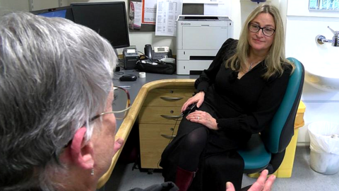 Blonde haired lady talking to a patient in a GP surgery consultant room