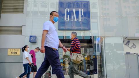 Customers walk outside a GAP store with protective masks in Beijing, China.