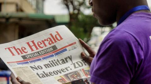 A man reads the front page of a special edition of The Herald newspaper about the crisis in Zimbabwe