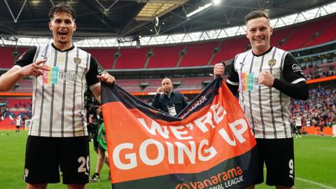 Notts County's Ruben Rodrigues (left) and Macaulay Langstaff hold up a 'we're going up' flag after winning the National League promotion final at Wembley