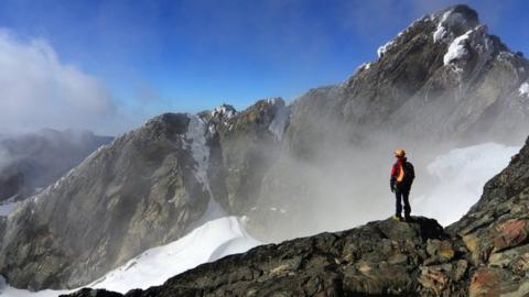 A hiker looking over to the summit of Margherita Peak, Rwenzori.