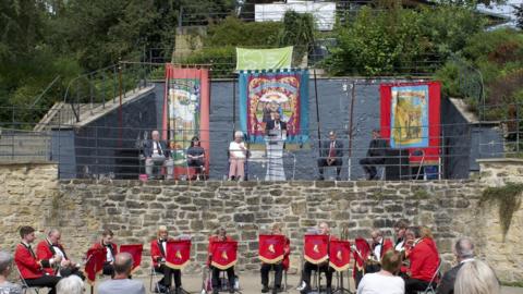 Brass band musicians and dignitaries in the park